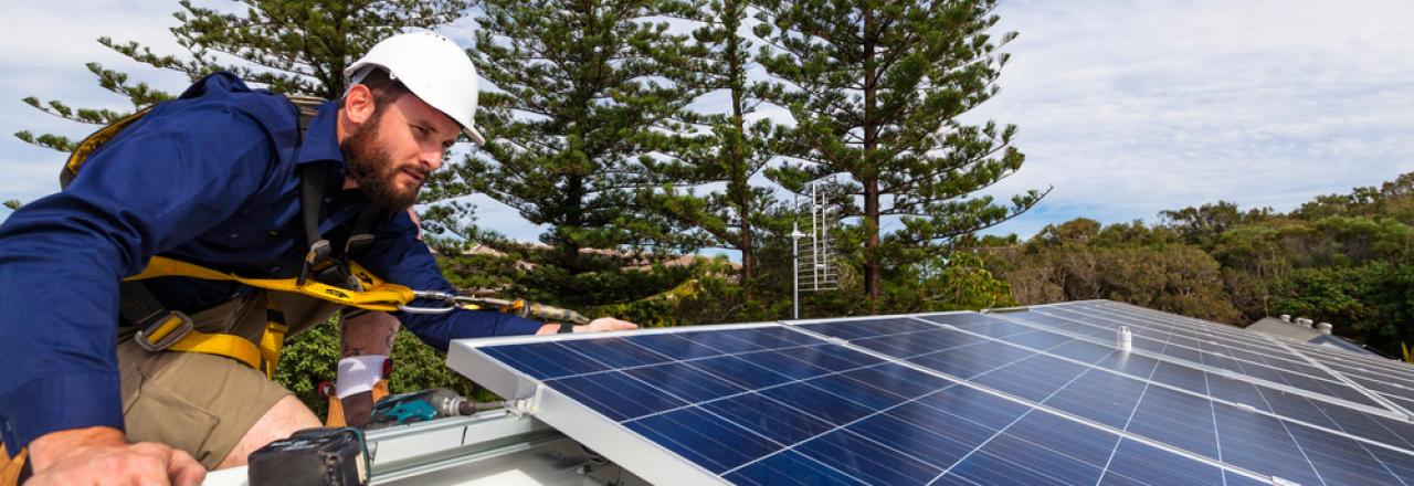 technician installing solar panels on roof