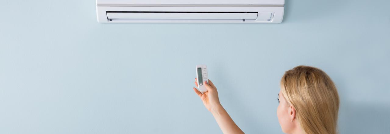 woman using remote to control air conditioning heat pump in home